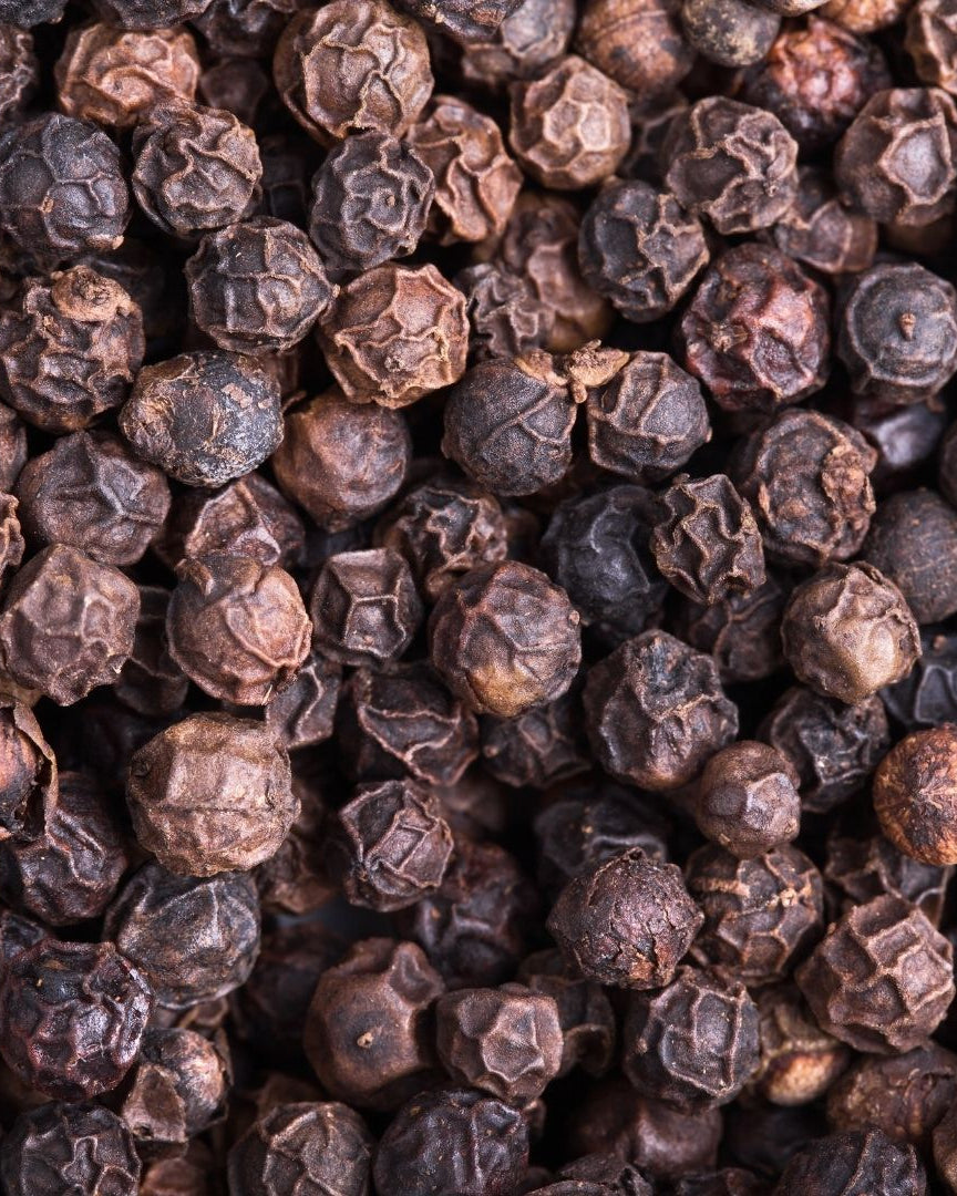 A close-up image of whole black peppercorns.