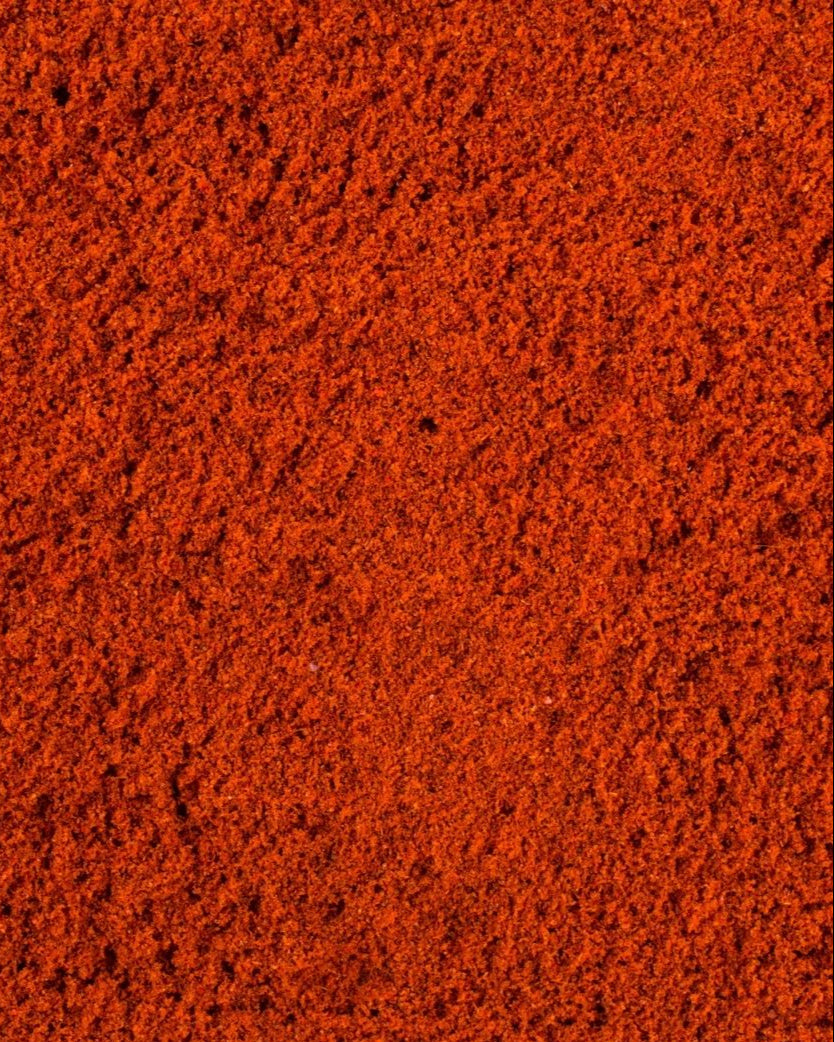 A close-up image of chili powder, with a textured, granular appearance, indicating a spicy flavor.